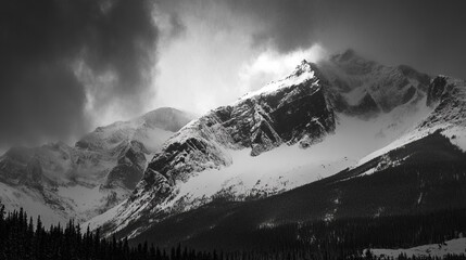 Dramatic black and white photograph of a snow-capped mountain range under a stormy sky, sunlight piercing through the clouds