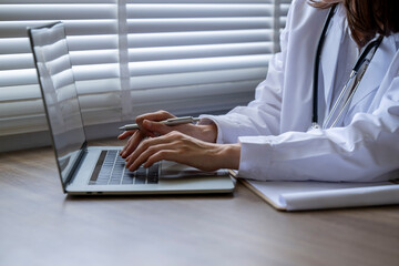 A woman is typing on a laptop computer