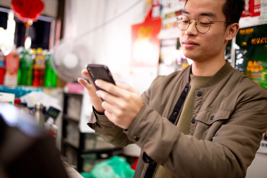 Asian grocery store manager typing on phone