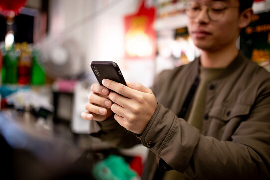 Asian grocery store manager typing on phone