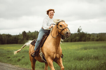 A woman is skillfully riding a horse gracefully in a lush field