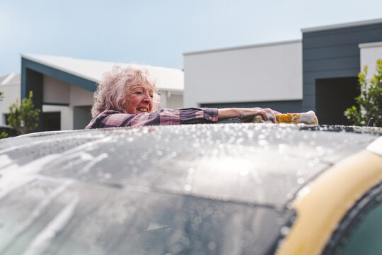 senior woman drying the roof of her car