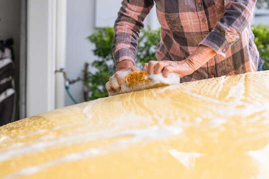 woman washing her car with a soapy sponge
