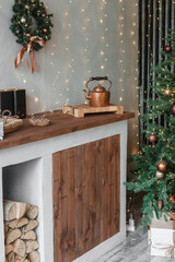 Home New Year's interior. Christmas tree with gifts, decorated with garlands in the kitchen. Cozy atmosphere of a home holiday, loft design of the room, Scandinavian style.