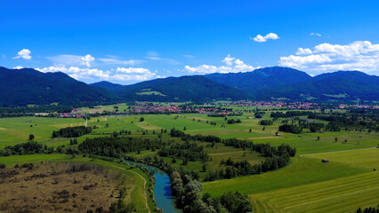 Scenic Landscape Featuring Rolling Hills, a River, and a Small Village Under a Vibrant Blue Sky in...