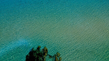Clear Turquoise Water Gently Ripples in a Serene Coastal Setting With Rocky Edges Under Bright Sunlight