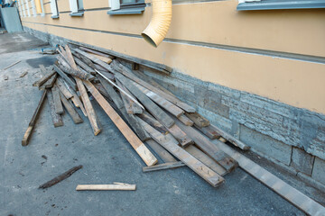 Obraz premium Pile of wood is on the ground next to a building. The wood is scattered and he is in disarray. The scene gives off a sense of chaos and disorganization