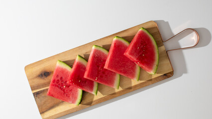 Slices of luscious watermelon languish on rustic board, evoking summer picnics, National Watermelon...