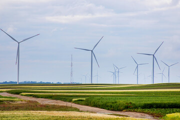 Majestic wind turbines silently dance over lush fields, embodying Earth Day's renewable energy...