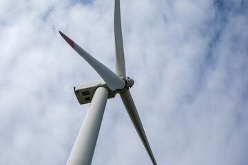 Under the brooding canvas sky, a solitary wind turbine spins gracefully, whispering eco-solstice...
