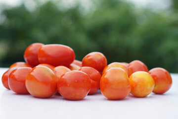 Freshly washed organic tomatoes are stacked on a clean surface outdoors. Concept of pesticide-free garden produce, ideal for healthy cooking and nutritious lifestyle. Natural and rich in antioxidants.