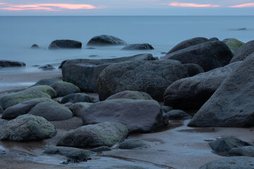 Obraz premium Serene Coastal View with Rocks and Calm Seascape at Sunset