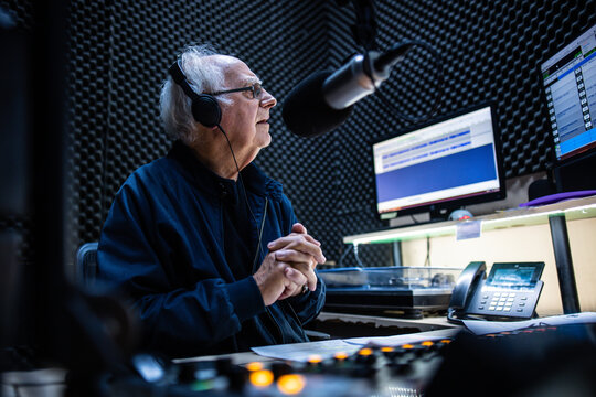 An elderly caucasian man DJs and presents his music show on live radio in Melbourne, Australia