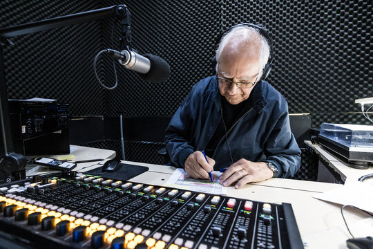 An elderly caucasian man DJs and presents his music show on live radio in Melbourne, Australia