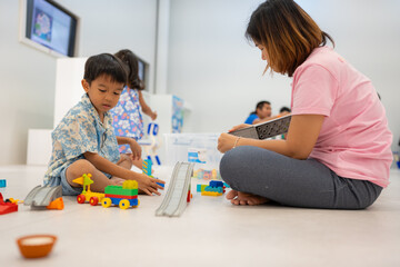 Mom with kids boy and girl learnning build color toy block in classroom