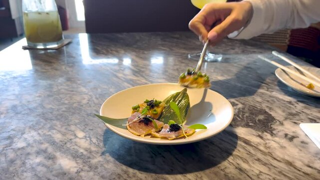 Serving fresh fancy small bite tapas in a plate with hand and fork, tasty European coastal food scene at table