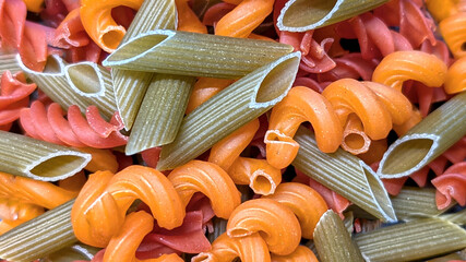 Background with Colorful shapes of organic vegetable pasta with vibrant colors like orange and...