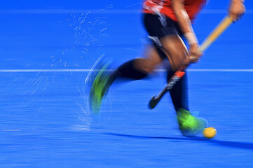 Slow shutter speed effect.  Motion blur. movement of hockey player carrying hockey ball on a wet...