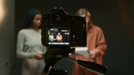 Close-up shot of camera recording two actors reading scripts while rehearsing their roles on set in studio