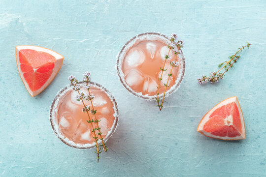 Salty Dog cocktail with fresh grapefruit juice, lime juice, and thyme, overhead flat lay shot with fruit slices