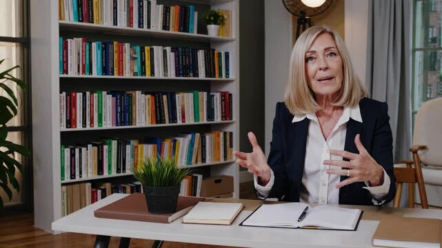 Professional woman in a library setting, seated at a desk. Eye-level camera angle, perfect for an informative video or interview setting.
