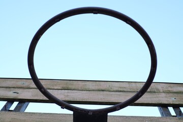 Minimalist abstract composition of basketball hoop against pale blue sky