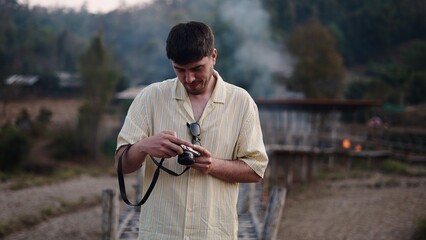 Young man reviewing pictures on his analog camera during a journey in a remote village
