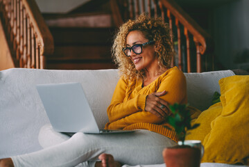 Confident woman working remotely from home while sitting on the sofa with her laptop. A peaceful...