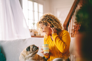 Happy woman relaxing at home on the sofa with her beloved dog by her side. A warm, joyful moment of...