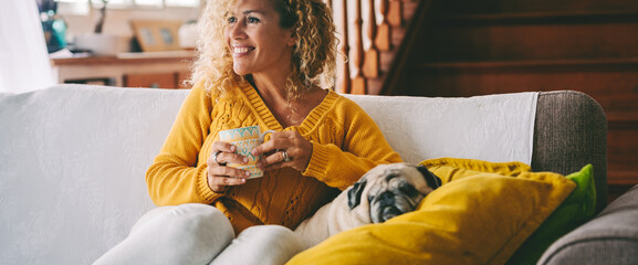 Happy woman relaxing at home on the sofa with her beloved dog by her side. A warm, joyful moment of...
