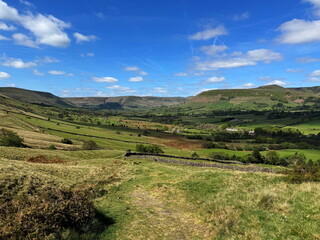 Panorama of the Peak District with green hills, deep valleys and a worn footpath in the foreground...