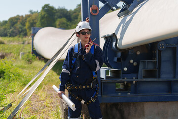 Engineers in safety gear conduct a detailed inspection of wind turbine blades at a construction...