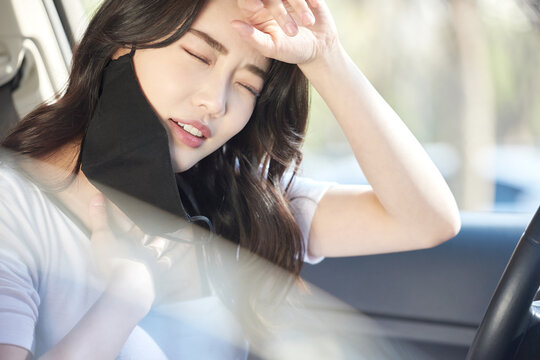Young Woman Sitting in Car Removing Black Face Mask and Taking a Deep Breath Through the Window
