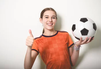 Fotobehang one caucasian young soccer player girl standing in studio gray background © Louis-Photo
