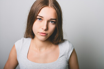 Portrait of teenage girl in casual t-shirt on light background in studio.