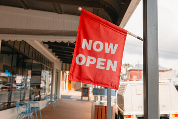 Vibrant red Now Open sign out front of gift shop in small regional town