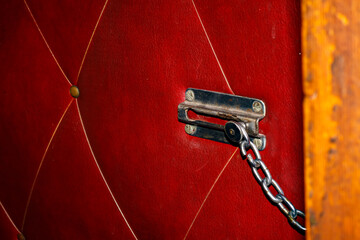 Old Door Chain Lock on Red Leather Upholstered Door — Vintage Security Lock, Interior Safety Element, Retro Hardware, Home Entrance Protection