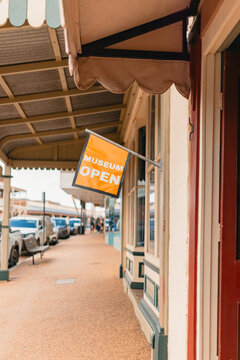Yellow museum Open sign along footpath in main street of small historic Australian town