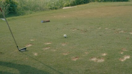 A male golfer's feet slowly approaches a teed-up ball on a divot-filled tee box, carrying an iron. Captured in slow motion, this clip highlights course conditions and golfer focus before the shot.