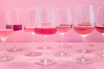 Rose wine tasting, a variety of hues and tints, side view on a pink background, an assortment of different wine glasses