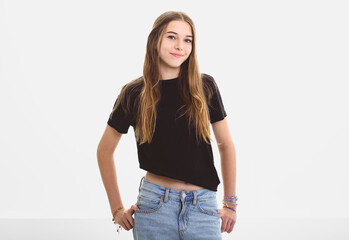 Obraz premium Portrait of teenage girl in casual black t-shirt on light background in studio.