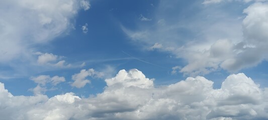 Obraz premium Fluffy clouds in a bright blue sky on a sunny day in the city 