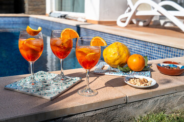 Aperol Spritz on sunny poolside table with fresh citrus