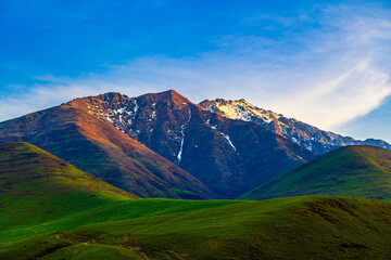Majestic mountain range with snow-capped peaks and green hills in Kyrgyzstan