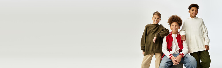 Joyful little boys in trendy outfits celebrate friendship with vibrant smiles and playful poses