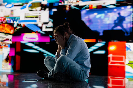 Paranoid guy suffers from emotional damage caused by obsessive social media use. Young man being overwhelmed by excessive information and comparison affecting his self esteem, manipulation.