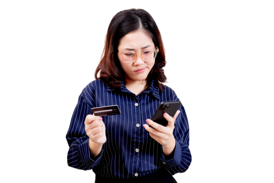 Asian young beautiful woman wearing glasses and a striped shirt looks confused while holding a credit card in one hand and a smartphone in the other.