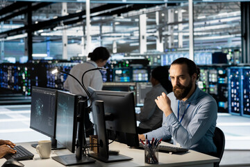 Technician using PC in data center to update server tech, configuring equipment using software...