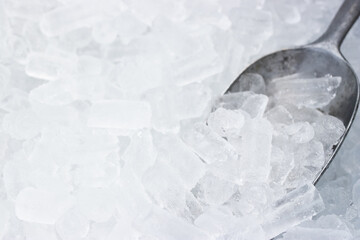 Cylindrical ice cubes with a metal scoop in an ice bin, commonly used for chilling beverages or food in restaurants.