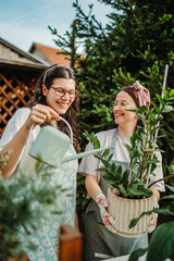 Two female friends or sisters taking care of plants with water can and mister	
